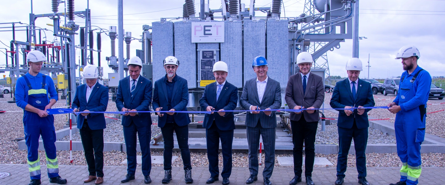 grupa mężczyzn stoi przed urządzeniami energetycznymi i przecina wstęgę jako symbol otwarcia GPZ czyli Głównego Punktu Zasilania