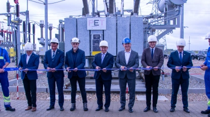 grupa mężczyzn stoi przed urządzeniami energetycznymi i przecina wstęgę jako symbol otwarcia GPZ czyli Głównego Punktu Zasilania