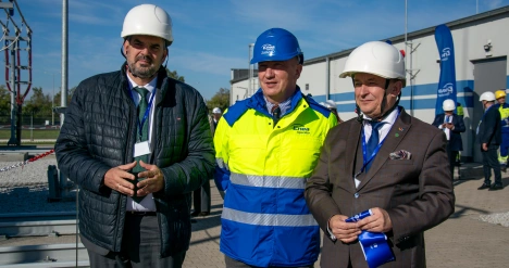 Trzech mężczyzn stoją przed GPZ ENEA Operator z oznakowaniem projektu współfinansowanego ze środków Unii Europejskiej,