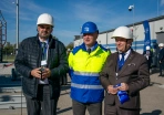 Trzech mężczyzn stoją przed GPZ ENEA Operator z oznakowaniem projektu współfinansowanego ze środków Unii Europejskiej,